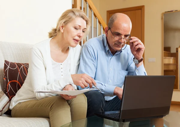 Homme et femme lisant ensemble des documents financiers — Photo