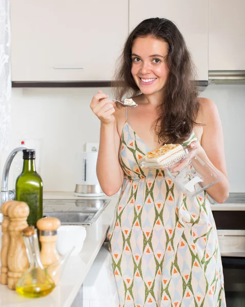 Mulher comer biscoito na cozinha — Fotografia de Stock