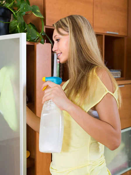 Blond meisje schoonmaken glazen deur van meubilair — Stockfoto