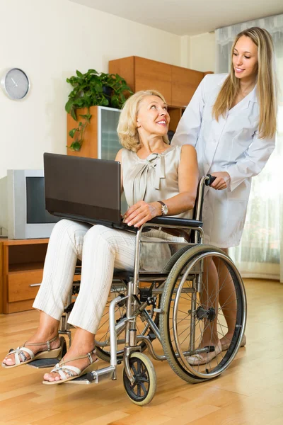 Social worker and invalid with laptop — Stock Photo, Image