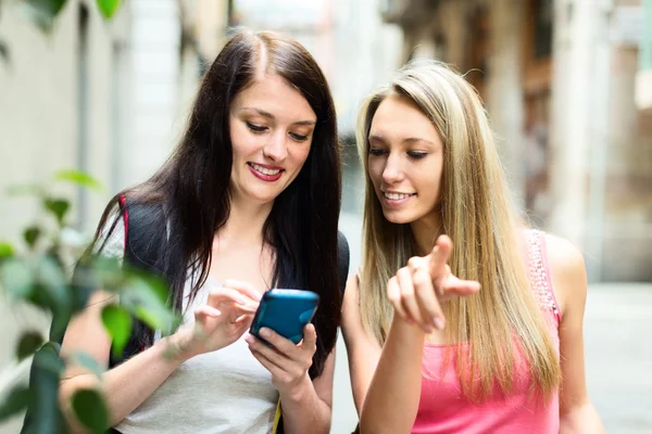 Dvě hezké dívky najít cestu s smartphone — Stock fotografie
