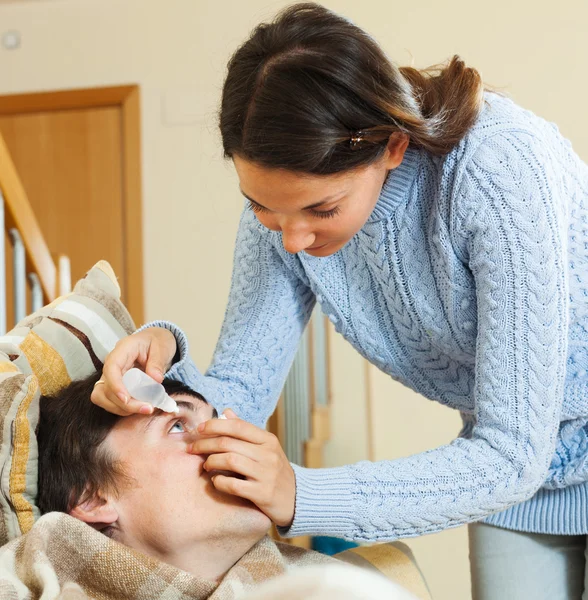 Frau tropft Collyrium auf Mann — Stockfoto