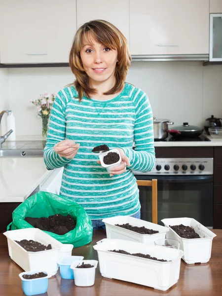 Chica en verde haciendo tierra para plántulas — Foto de Stock