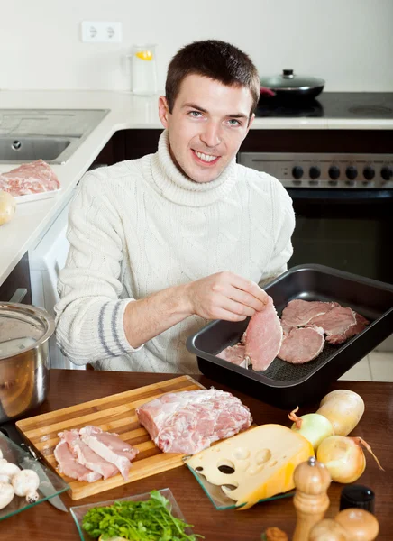 Guy with meat in kitchen — Stock Photo, Image