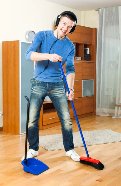 Cara feliz com dustpan e escova em casa — Fotografia de Stock