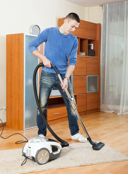 Homem de limpeza com aspirador na sala de estar — Fotografia de Stock