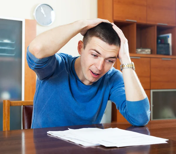 Sad shocked guy looking at document at home — Stock Photo, Image