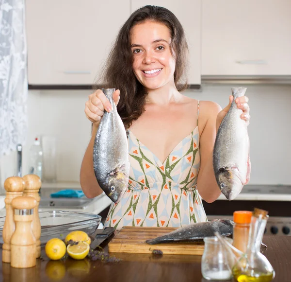 Mujer cocinando pescado en la cocina — Foto de Stock