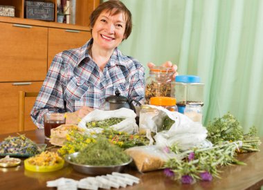 Mature woman with herbs at table clipart