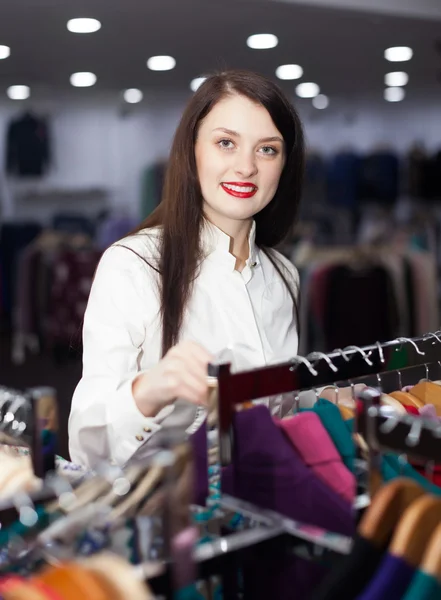 Mujer de pelo largo elegir la ropa en la tienda — Foto de Stock