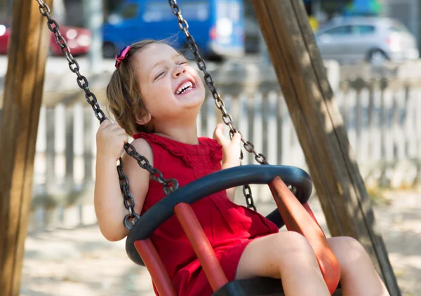 Laughing girl in red dres on  swing — Stock Photo, Image