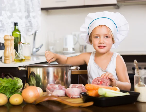 Criança pequena no chapéu de cozinheiro que cozinha sopa — Fotografia de Stock