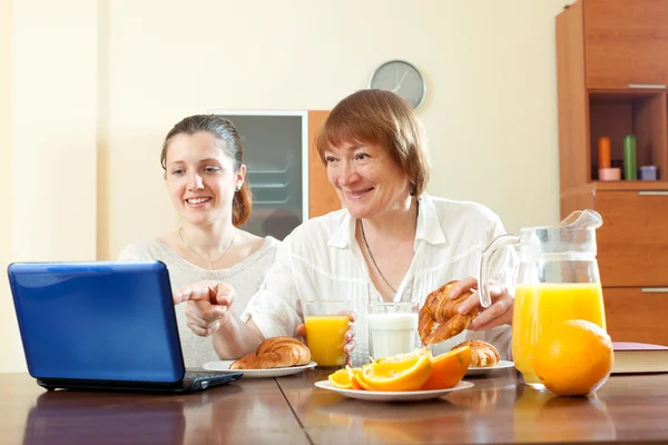 Två glada kvinnor använder laptop under frukosten — Stockfoto