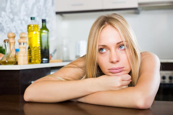 Triste giovane donna seduta in cucina — Foto Stock