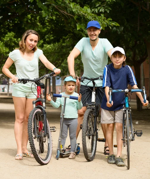 Vierköpfige Familie mit Fahrrädern und Motorroller im Urlaub — Stockfoto