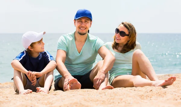 Föräldrar med pojke sitter på sea sand — Stockfoto