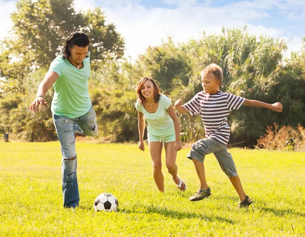 Família de três com adolescente jogando futebol — Fotografia de Stock