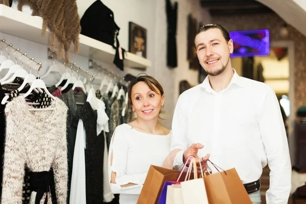 Smiling couple with bags at clothing boutique — Stock Photo, Image