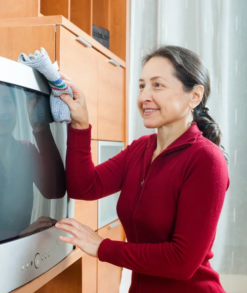 Reife Frau beim Abstauben des Fernsehers — Stockfoto