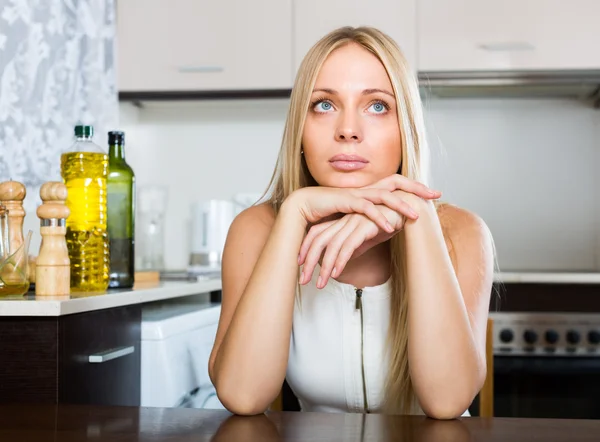 Triste giovane donna seduta in cucina — Foto Stock