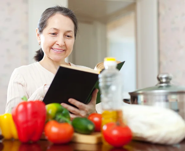 Woman cooking with cookbook — Stock Photo, Image