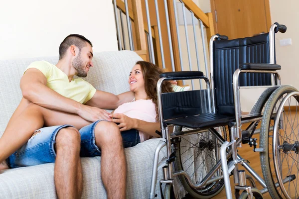 Пара на диване рядом с инвалидной коляской — стоковое фото