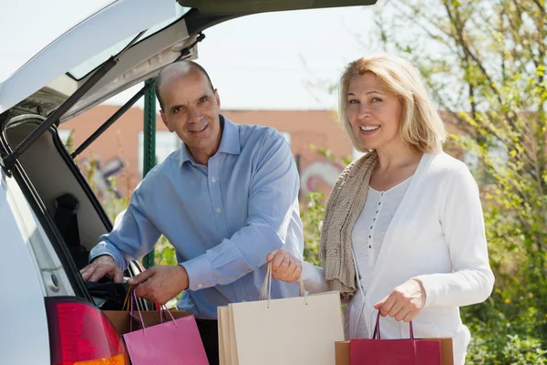 Smiling senior couple with bags — Stock Photo, Image