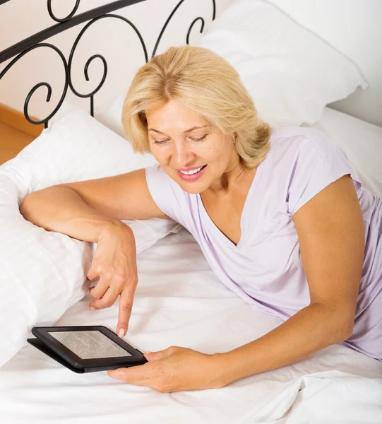 Mature woman with eBook laying — Stock Photo, Image