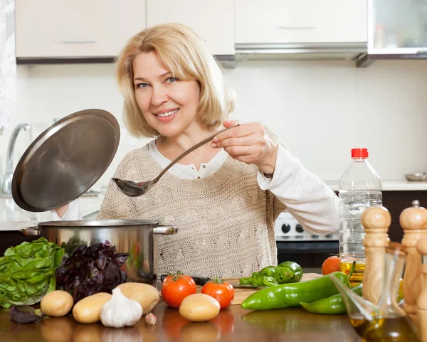 Glimlachend volwassen vrouw soep koken — Stockfoto