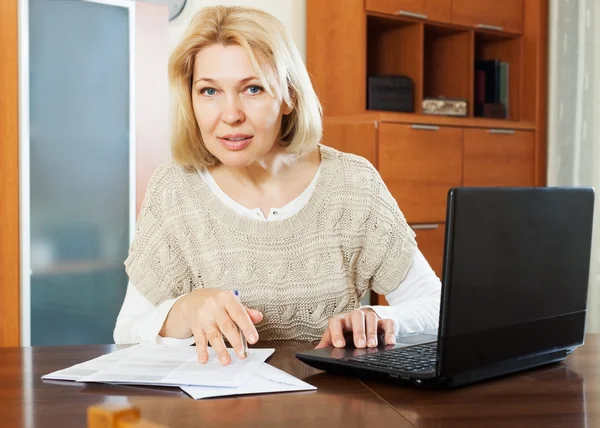 Женщина с ноутбуком и финансовыми документами — стоковое фото