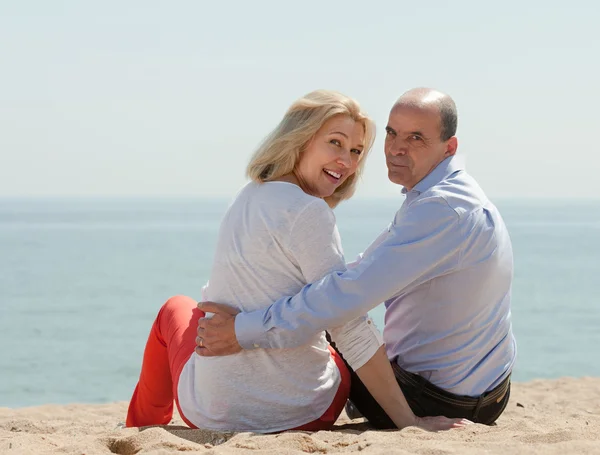 Ältere Liebhaber sitzen am Strand — Stockfoto