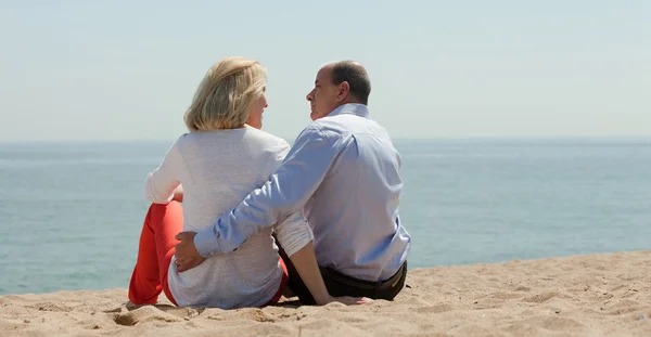 成熟的恋人坐在海滩上 — 图库照片