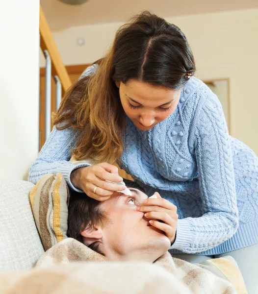 Frau tropft Collyrium auf Mann — Stockfoto