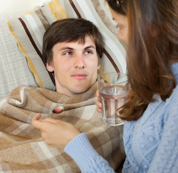 Woman giving medicinal syrup to  husband — Stock Photo, Image