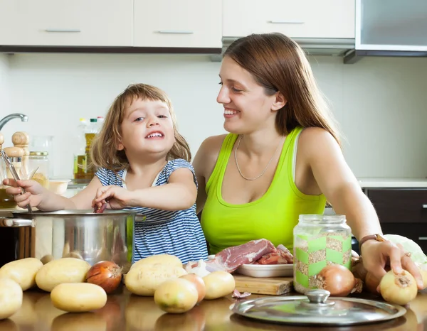 Mãe feliz com filha cozinhar sopa — Fotografia de Stock