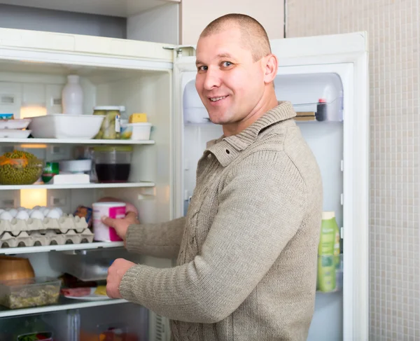 Mann nimmt Lebensmittel aus Kühlschrank — Stockfoto