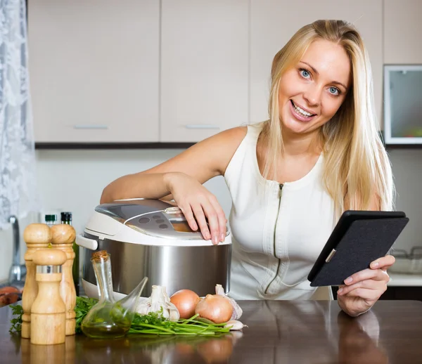 Ev hanımı okuma ereader ve pişirme — Stok fotoğraf