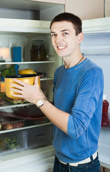 Людина з каструлею біля холодильника — стокове фото