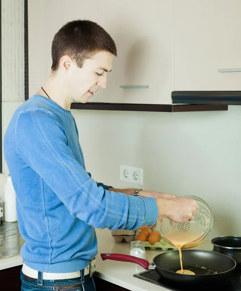 Guy pouring dough in frying pan — Stock Photo, Image
