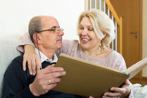 Senior spouses with picture album indoor — Stock Photo, Image
