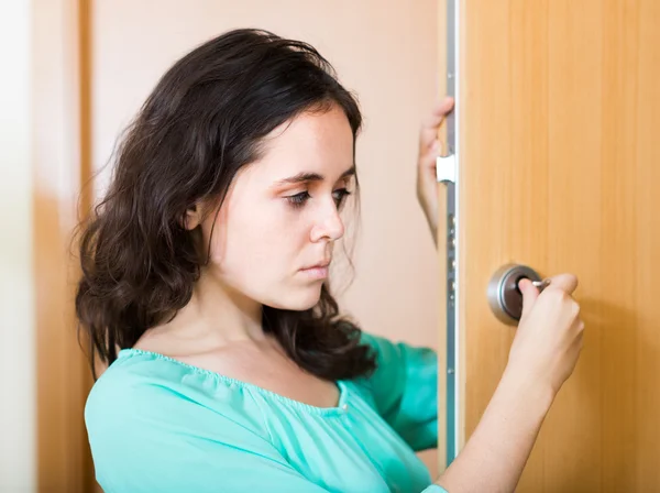 Brunette looking at broken lock of door — Stock Photo, Image