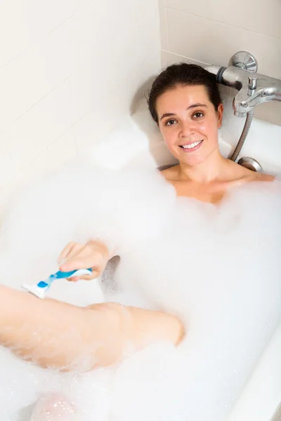 Жінка голиться ноги в ванній — стокове фото