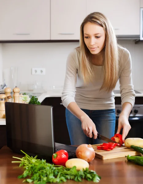 Casual kvinna använder bärbar dator medan matlagning — Stockfoto