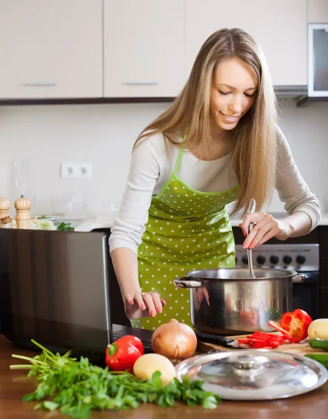 Mulher cozinhar sopa com laptop — Fotografia de Stock