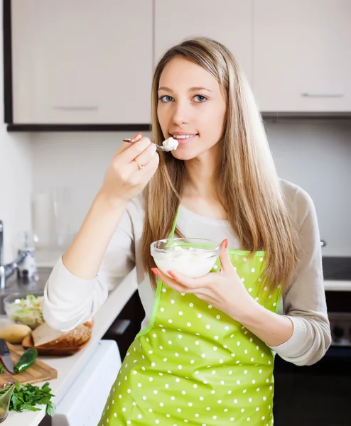 Woman in apron eating cottage cheese — Stock Photo, Image