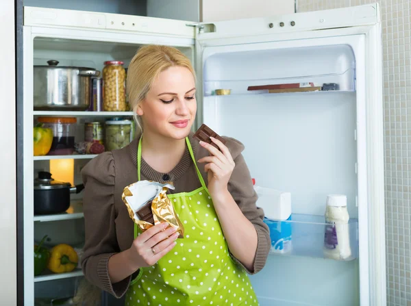 Vrouw eten chocolade uit de koelkast — Stockfoto