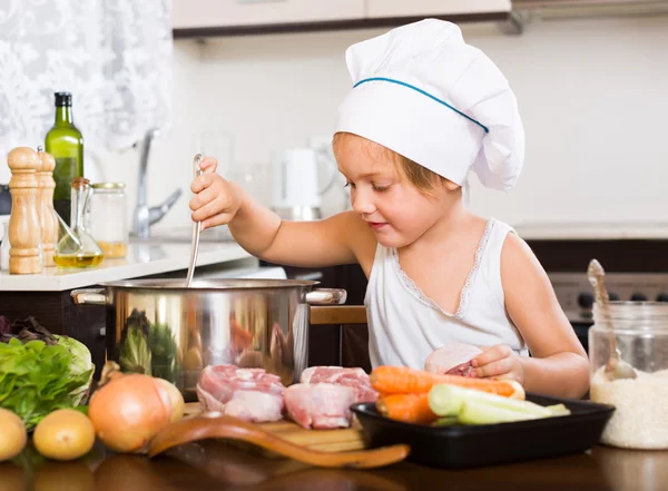 Meisje van de baby koken met vlees — Stockfoto