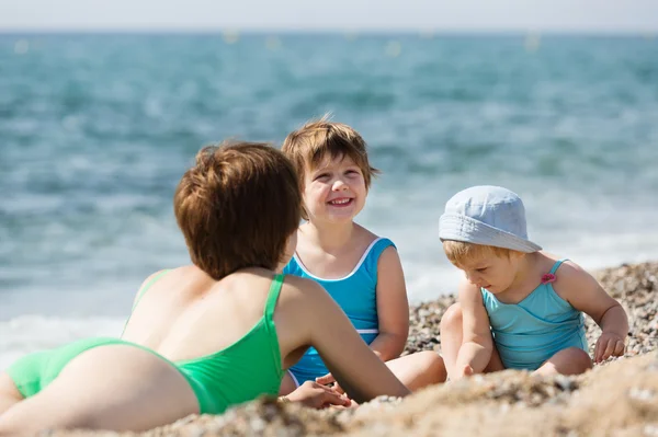 Мать с счастливыми детьми на пляже — стоковое фото