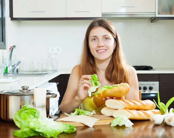 Mulher feliz cozinhar sanduíches com alface — Fotografia de Stock