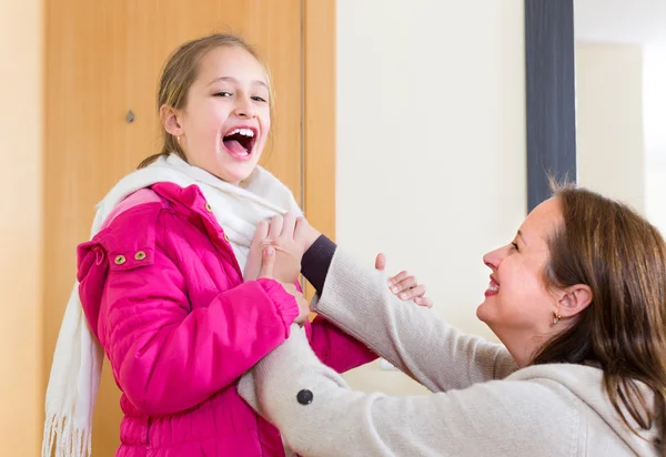 Vrouw meisje om omhoog te kleden helpen — Stockfoto